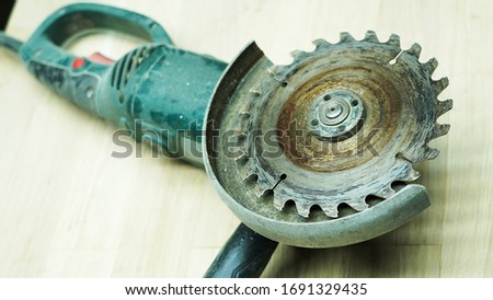 Close-up of a saw on a table. A round iron saw with sharp teeth for working with wood at home against a light wood background. A working old, dirty electric tool