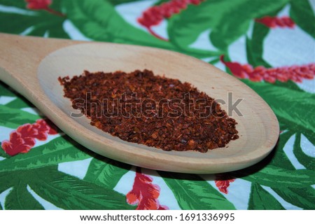 Moscow, Russia-03/2020: Isolated hot and spicy chili (spice) in a wooden spoon on a colorful background (kitchen paper napkin). Closeup top view.