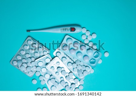 Tablets, pills and thermometer on a blue background. Flu cold concept. Healthcare medical concept. Medicine pill. Emergency medical treatment. Coronavirus medikament concept.