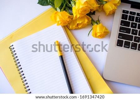 Office desk working space - Flat lay top view photo of working space with blank mock up notes, yellow roses on yellow background. Yellow color copy space working desk concept.