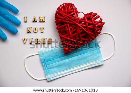 Blue medical glove, face protection mask, decorative heart made of twigs. The phrase made of wooden letters I'm not virus. Healthcare concept. Top view, flat lay.