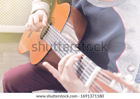 Learning to play the guitar. Music education. hands of a boy playing acoustic guitar. serious teenager in glasses trying to play indoors.