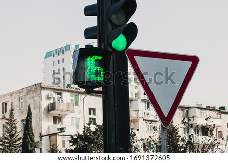 Green lighted Traffic light with the main road sign. Traffic light with stopwatch.16 seconds to stop.