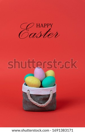 Colorful easter eggs with ceramic basket concept. Text Happy Easter on red background.