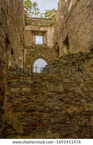 Ruined interior wall of Clifden Castle with an arched and square window, brick wall with rough texture, sunny spring day in County Galway, Ireland