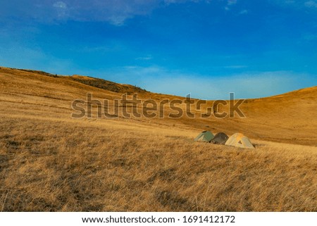 travel life style landscape picture of tent camp site in highland mountains plateau space yellow grass cover ground surface and blue sky background 