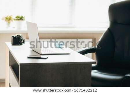 View on digital and film photo cameras lying next to laptop with  on light wooden table