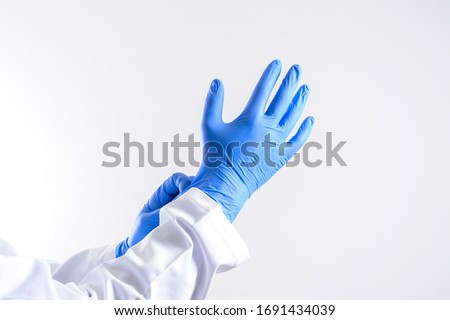 Doctor putting on sterile gloves isolated on white. scientist wearing glove. Human wearing glove on white background. blue rubber glove on a man hand isolated on white Royalty-Free Stock Photo #1691434039