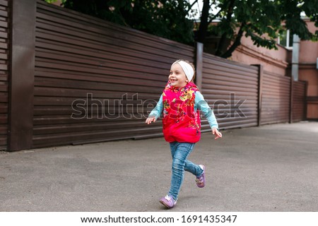 cute little girl heerfully spending time while running at city street on the summer day