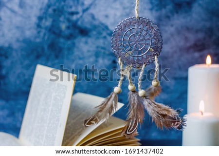 Dreamcatcher amulet feng shui. Dream catcher from metal and feathers against the background of burning candles. Background concept about magic, sorcery, esotericism, feng shui symbol Royalty-Free Stock Photo #1691437402