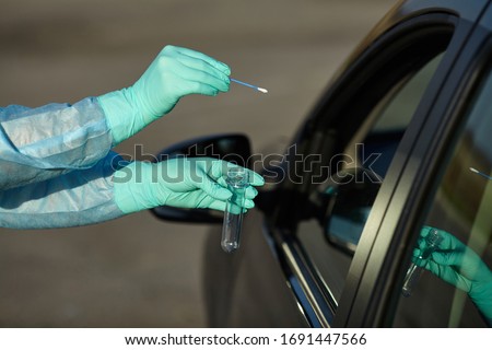 Epidemic concept COVID-19. Coronavirus Test Station. 
Medical worker in full protective gear takes sample from patient at a COVID-19 drive-thru test site. Testing is done by throat swab. Royalty-Free Stock Photo #1691447566