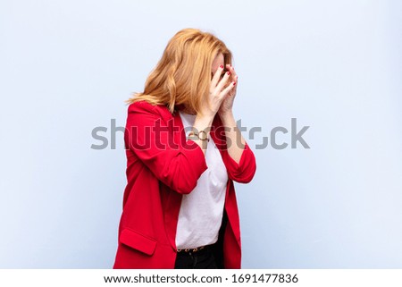 middle age woman covering eyes with hands with a sad, frustrated look of despair, crying, side view
