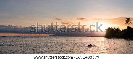 Swimmers in the sea under an amazing tropical sunset on a Caribbean beach in Guadeloupe island 