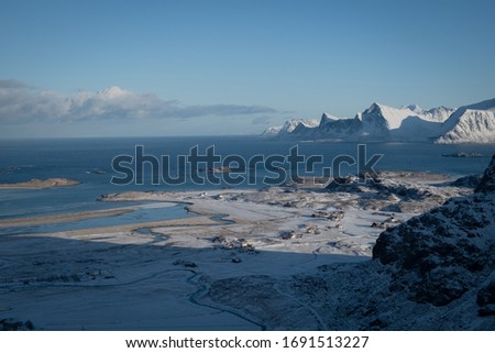Amazing  winter landscape of Lofoten Islands. Picture taken while hiking to famous Kvalvika beach. View to a coast line surrounded by mountains, river meander and small village. Touristic area. 