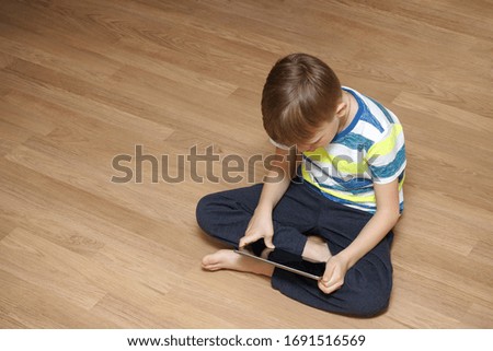 Modern generation. The child plays games or watches cartoons. A boy is playing with his tablet.