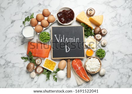 Flat lay composition with products rich in vitamin D on white marble table Royalty-Free Stock Photo #1691522041