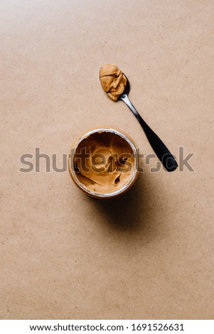Opened peanut butter with black spoon. Shelf vegetarian food concept. Minimal style photography.