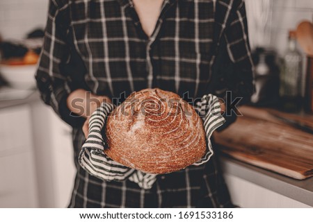 Homemade sourdough bread. Bright white kitchen. Bread on cutting board. Kitchen utensils. Craft authentic bread. Home cooking. Food preparation. Coronavirus covid-19 stay home isolation quarantine. Royalty-Free Stock Photo #1691533186
