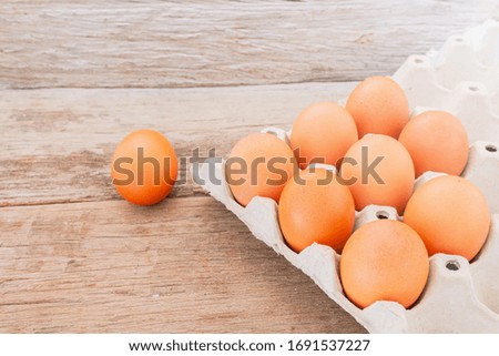 Close-up view of raw chicken eggs in egg box on wooden background.