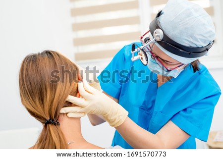 ENT doctor with tools, a mask and gloves examines the patient's ears. Otolaryngologist with her
tool Royalty-Free Stock Photo #1691570773