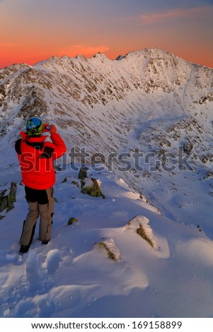 Sunset photographer taking pictures of snowy mountains