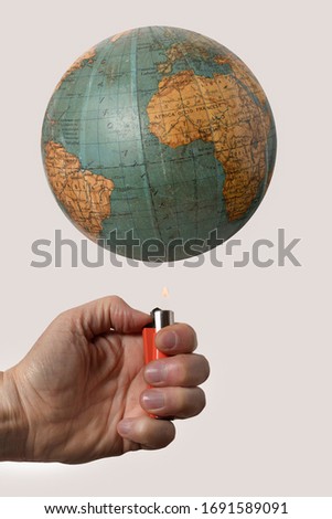 vintage world globe and under a hand with lighter on a white background to mean an environmental concept