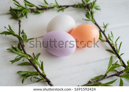 Happy Easter day. Easter decor. Easter eggs. Mindal sprigs. White wooden table. Lilac, orange and white eggs.