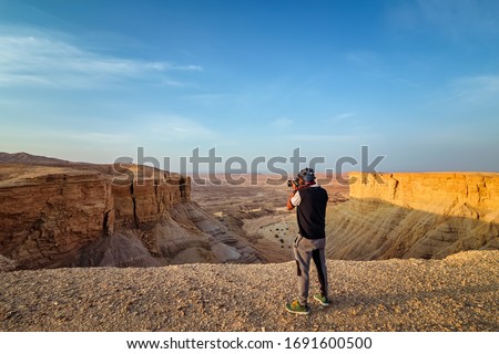 An adventure photographer in Edge of the World, a natural landmark and popular tourist destination near Riyadh -Saudi Arabia. selective focus on subject and background blurred.