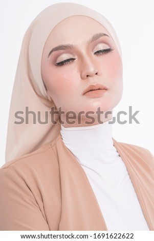 Studio portrait of young woman with hijab in light brown dress suit and high heel shoes on plain white background. Corporate people business working concept.
