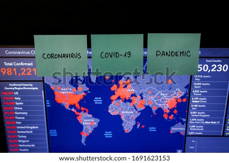 World Map and Statistics on the Laptop Screen with Sticky Notes Saying Coronavirus, COVID-19 and Pandemic