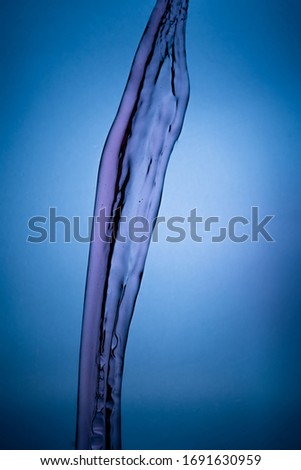 Beautiful splash of red wine close-up isolated on blue background vignetting