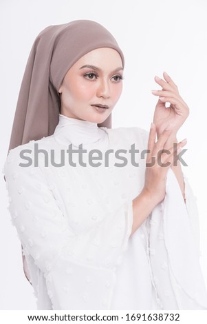 Studio portrait of beautiful young girl with hijab in white outfit and high heel shoes isolated over white background. 