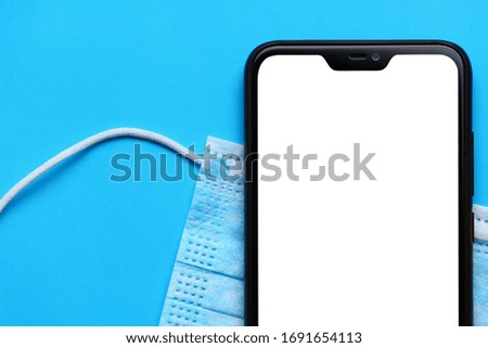Mask and part of a smartphone with an isolated white screen to insert an inscription, text or image on a blue background