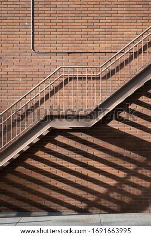 steel outdoor staircase casting shadow against red brick wall