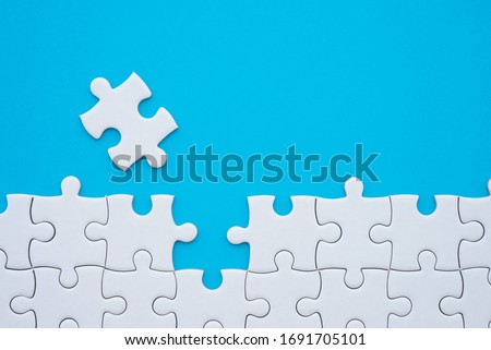 The last piece of jigsaw puzzle to complete task on blue background. Business strategy teamwork, problem solving concept. Teamwork is collaborative effort of team to achieve goal or complete mission.