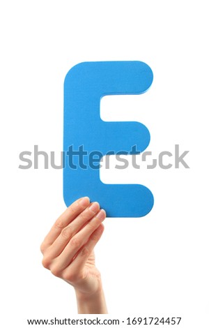 Capital letter E held in woman's hand on white background