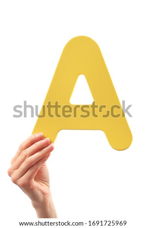 Capital letter held in woman's hand on white background