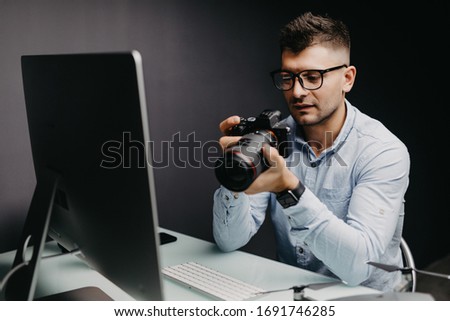 Young photographer busy retouching his images on his computer with his camera work from his home studio