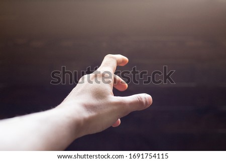hand reaching out POV shot on a dark wooden background  Royalty-Free Stock Photo #1691754115