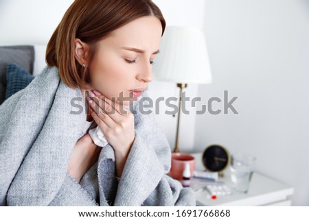 Sick woman covered in blanket at home in isolation at quarantine suffering from throat pain. Lymph glands, painful swallowing, pharyngitis, laryngeal swelling. First symptoms of covid-19 coronavirus Royalty-Free Stock Photo #1691766868