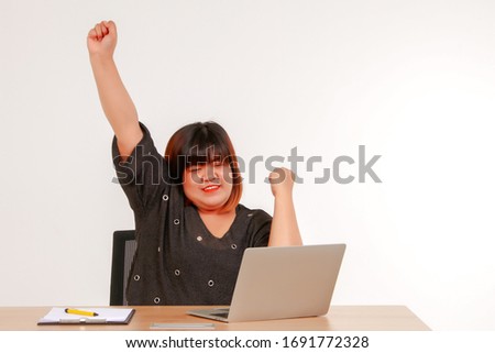 Concept work at home :
Fat Asian woman is sitting on a desk, using a laptop computer, expressing gratitude for her work to achieve her goals on white background