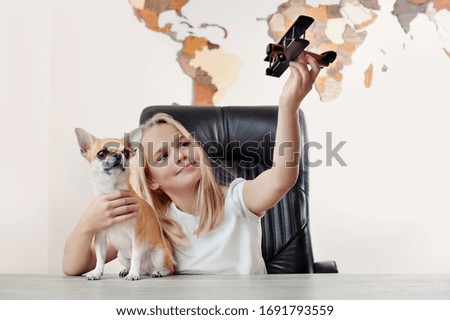 Blonde girl playing with wooden airplane with her chihuahua dog