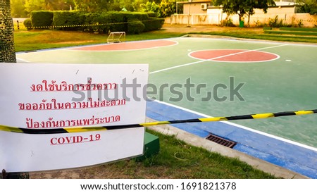A small football field that is closed.  In a white label  with a red text in Thai that "Temporary service is suspended Sorry for the inconvenience To prevent the spread of Covid-19. 
