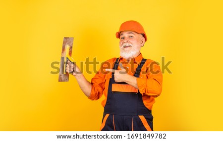 process of applying layer of putty. Plastering tools for plaster. plaster trowel spatula on yellow drywall plasterboard. Plasterer in working uniform plastering wall indoor. man with spatula.