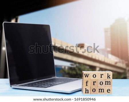 Wooden blocks with alphabet letter Work from home and notebook computer over blurry skytrain background. Stay at home for working concept.