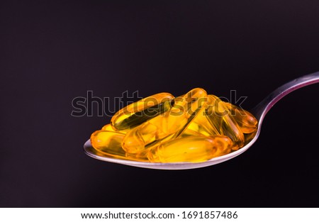 Useful omega 3 capsules in a spoon on a black background. Copy space.