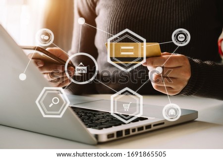 
Close up of Hand using credit card and smartphone, laptop computer on wooden desk with VR icon chart graph diagram
