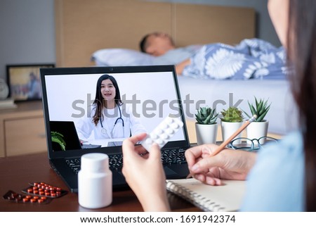 Patient's relatives use video conference, make online consultation with doctor on notebook computer, ask doctor about illness , medication via video call. Telehealth, Telemedicine and online hospital Royalty-Free Stock Photo #1691942374