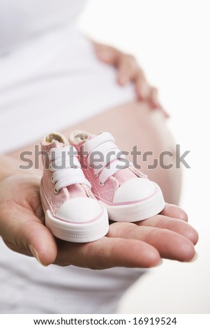 Pregnant woman holding pair of pink shoes for baby girl Royalty-Free Stock Photo #16919524