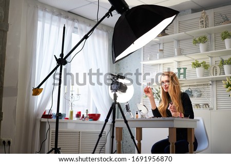 Beauty blogger woman filming daily make-up routine tutorial on camera. Influencer blonde girl live streaming cosmetics product review in home studio with professional lighting equipment. Vlogger job. Royalty-Free Stock Photo #1691956870